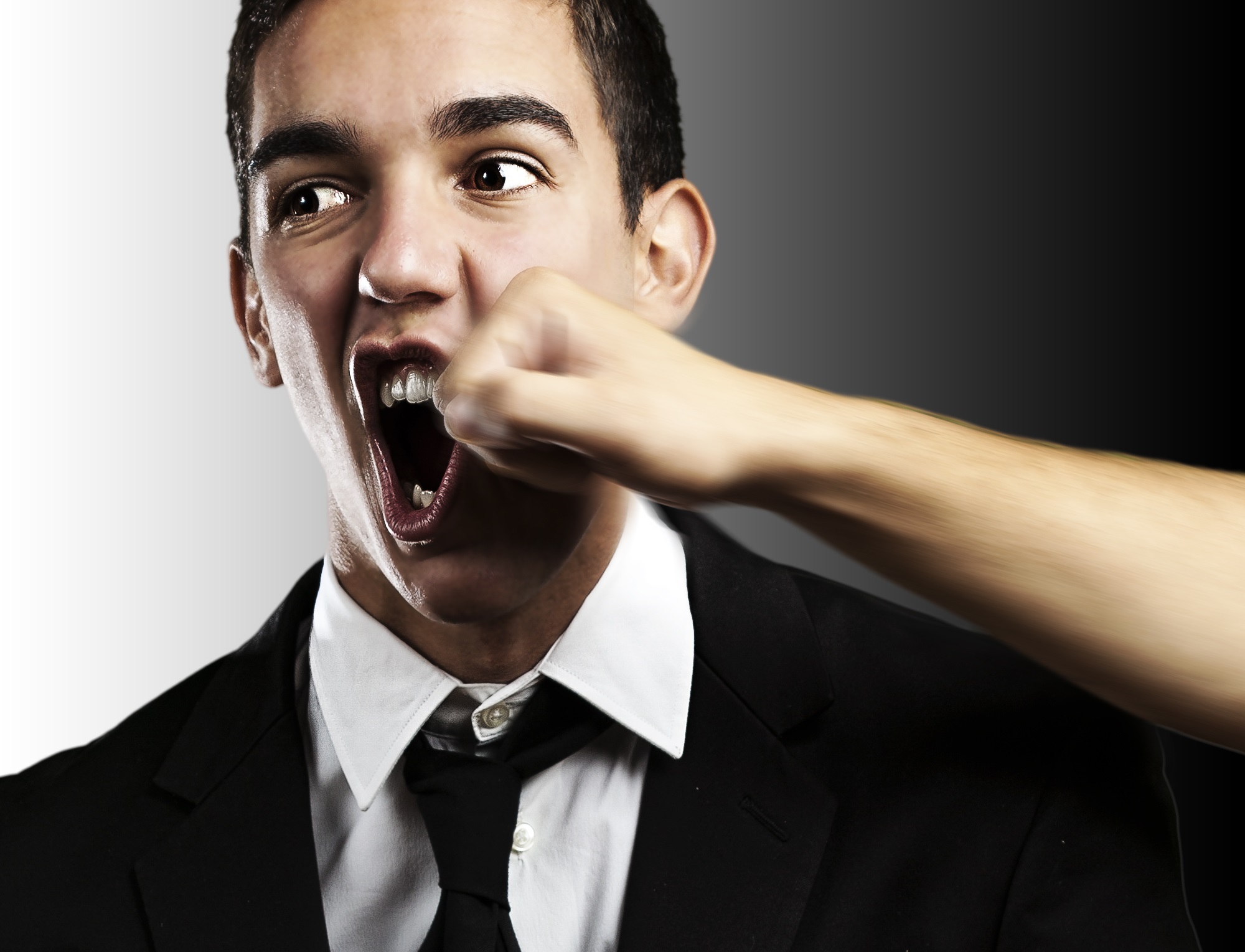 Young man wearing suit is getting punched on the face.