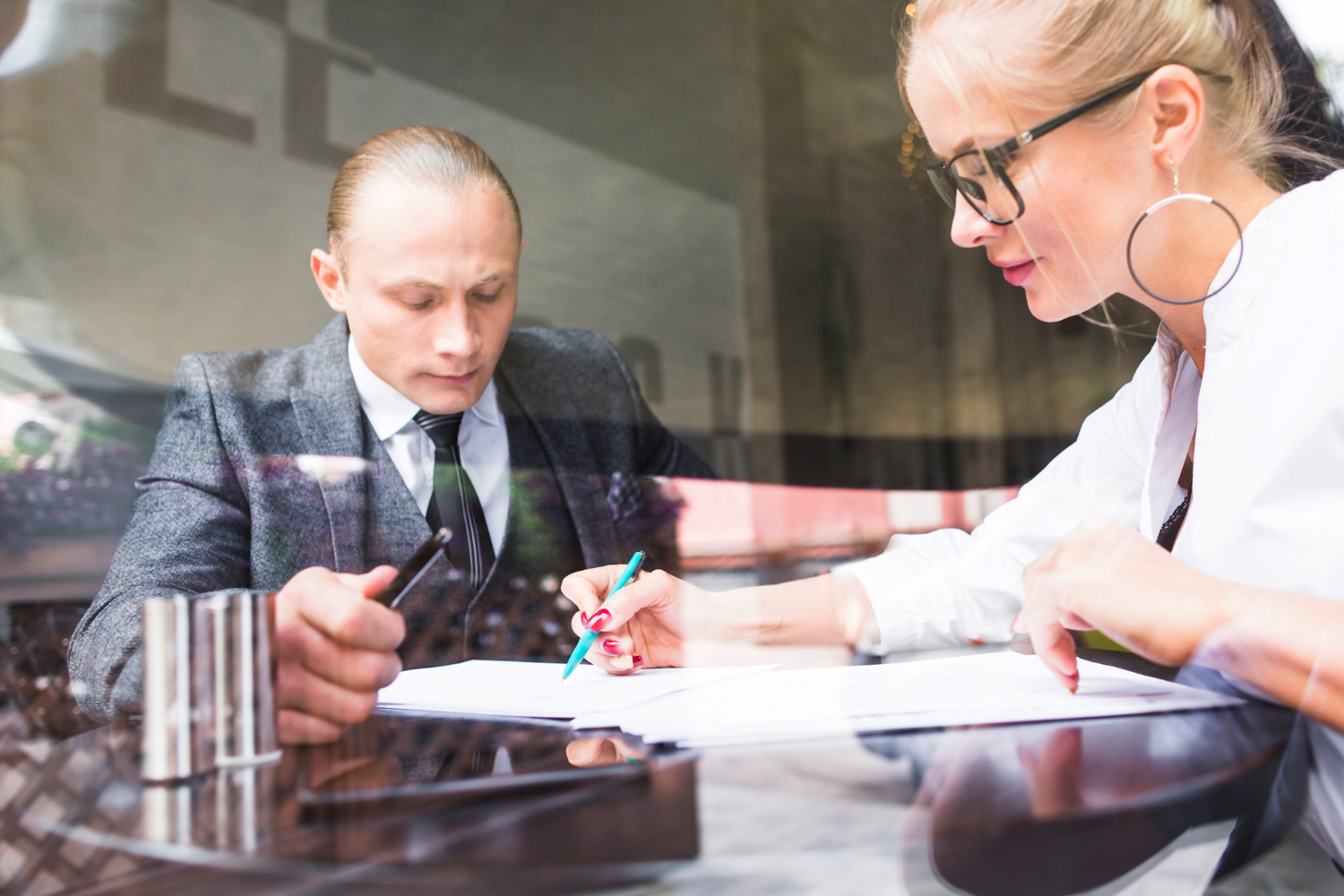 Two businesspeople examining document in restaurant.