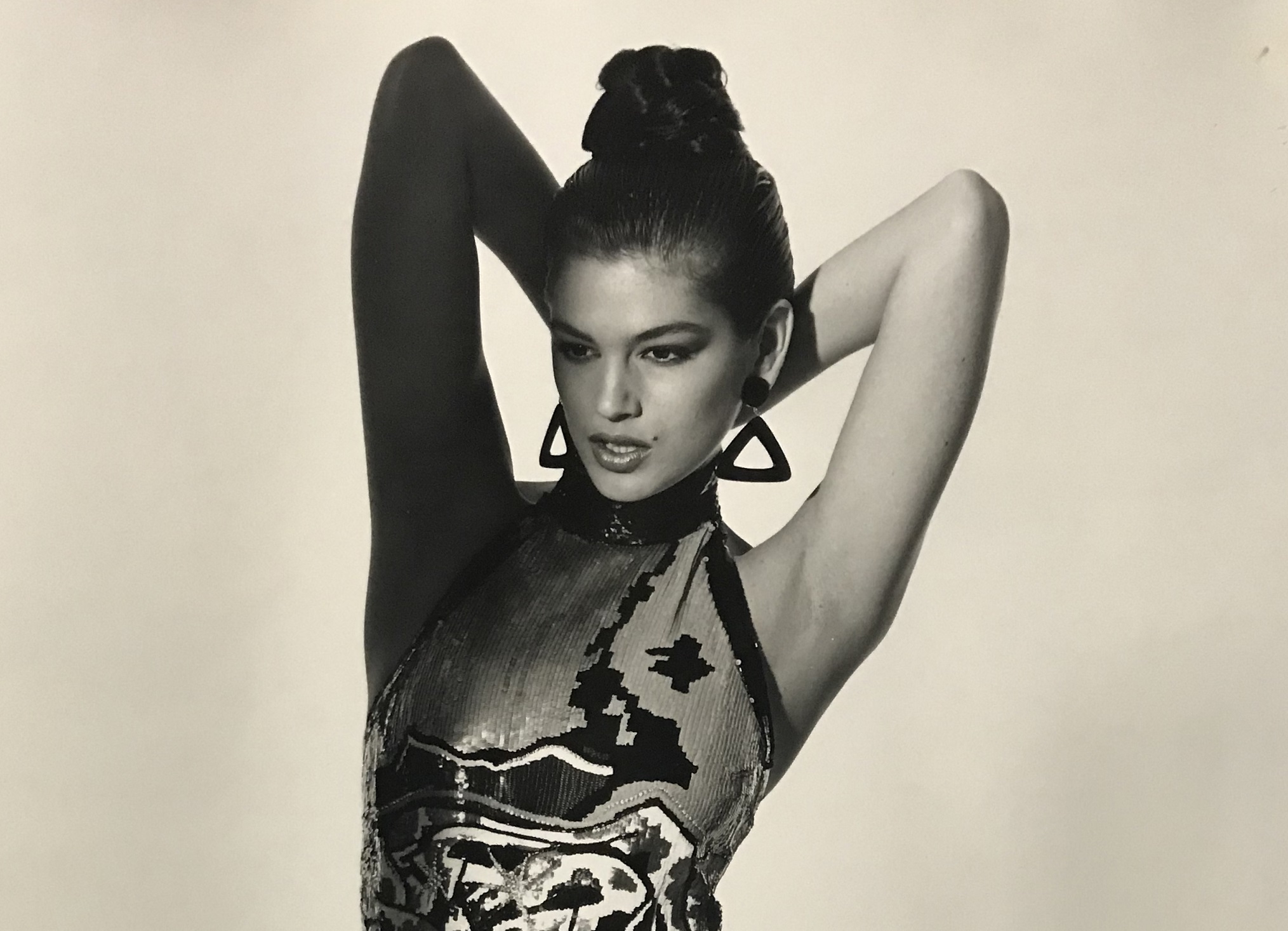 B&W photo of Cindy Crawford looking at side with arms up.