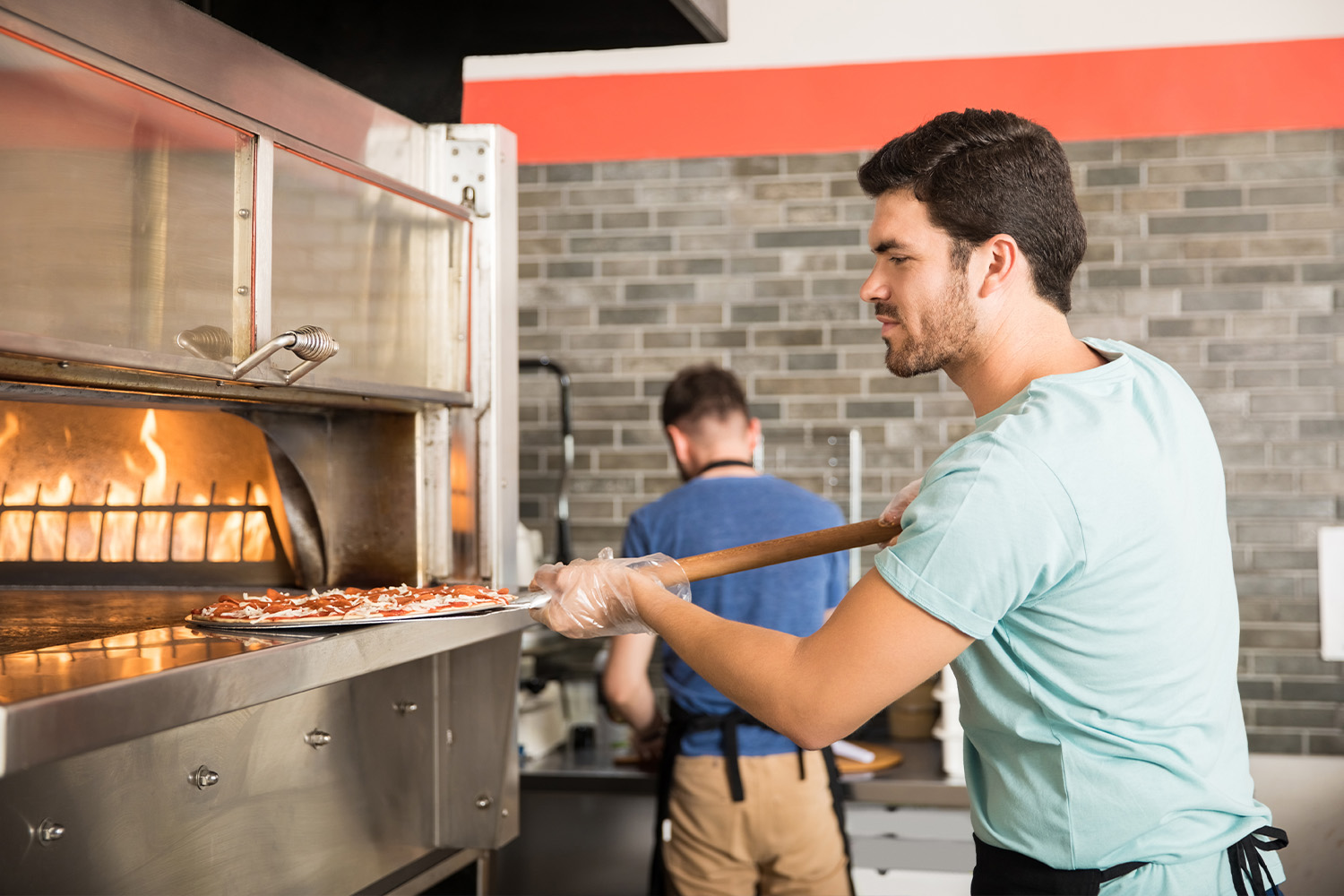 Man Putting A Pizza In The Oven