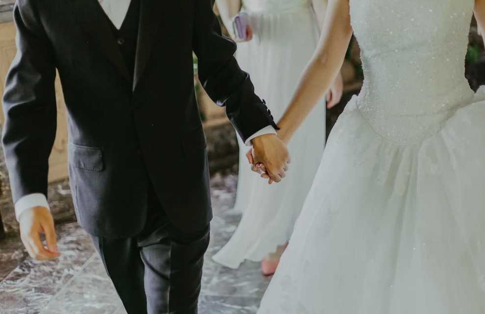 Bride and groom wearing wedding wear holding hands
