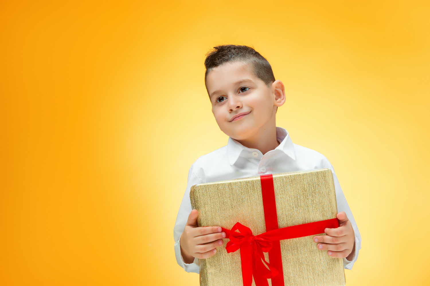 Happy kid is holding a present in hands on yellow background.