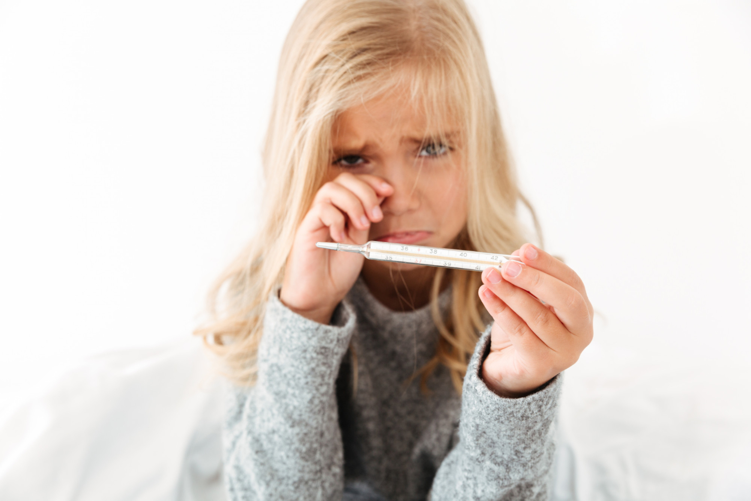 Small blonde girl is holding a mercury-filled thermometer.