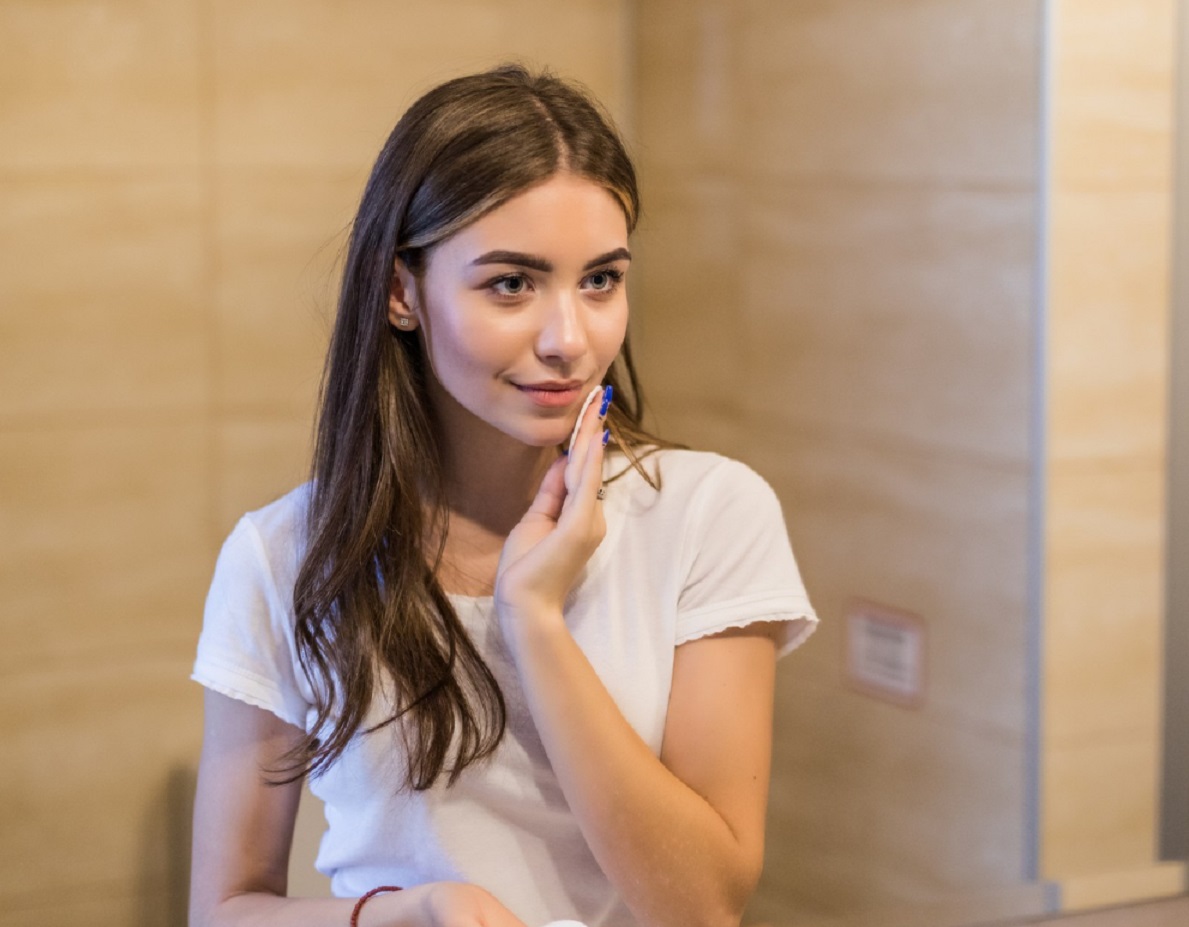 Young woman is looking at mirror at bathroom.