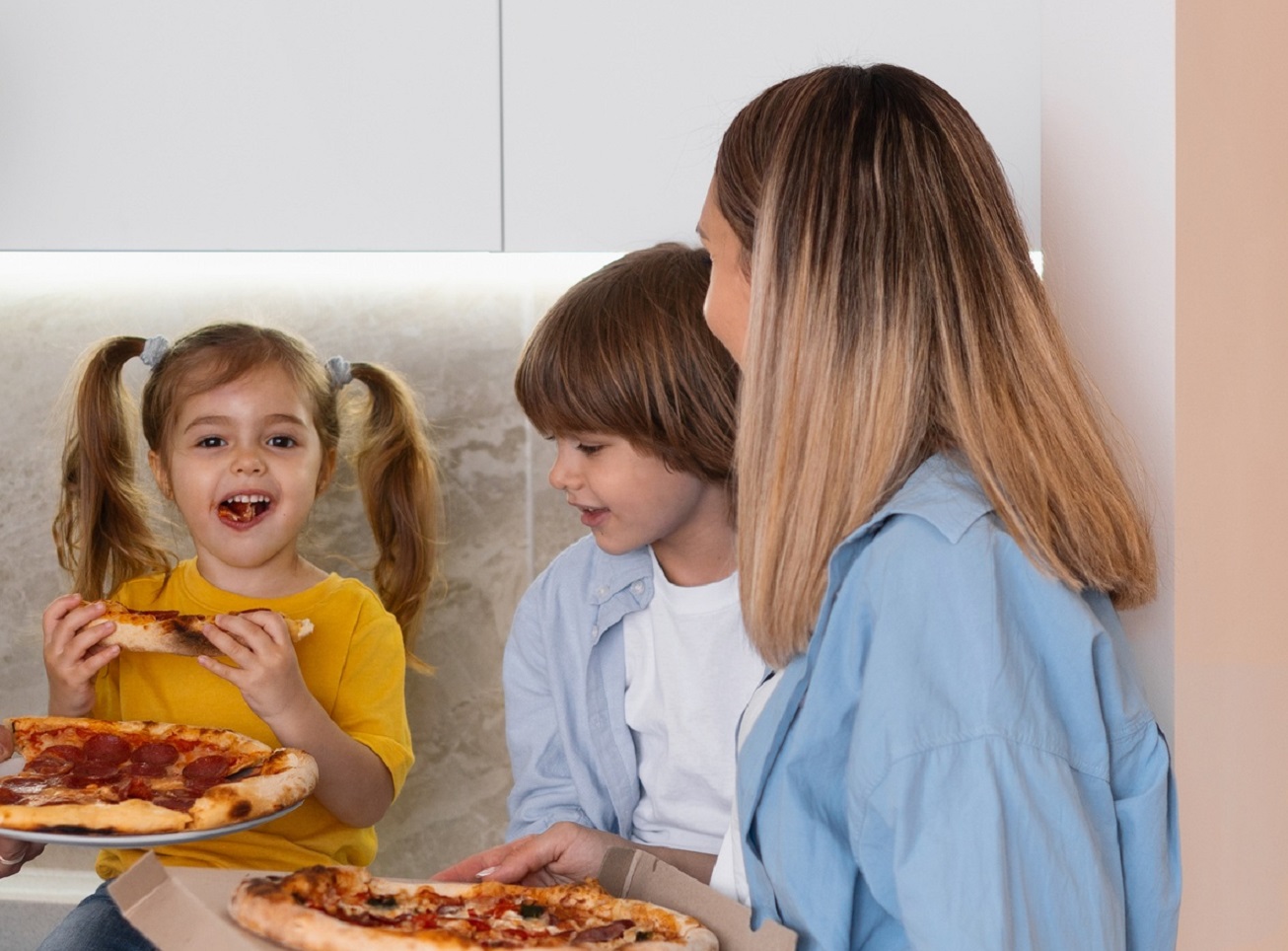 Mother and two kids are having a pizza for dinner.
