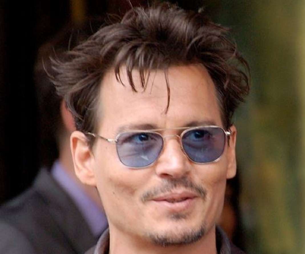 Johnny Depp wearing blue glasses is smiling - 2013