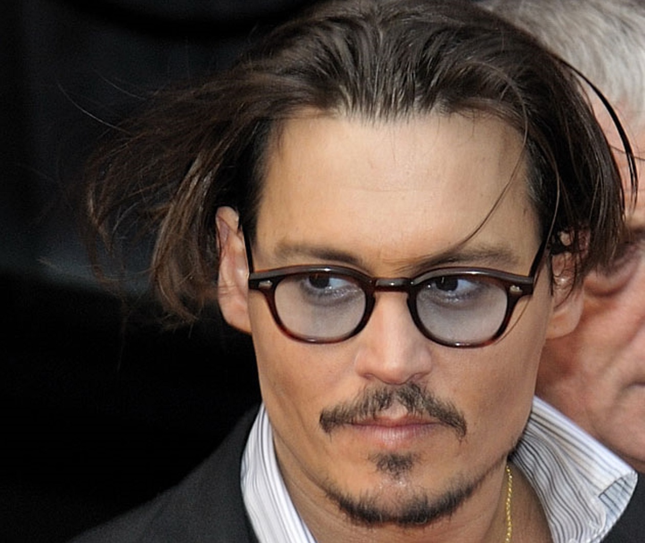 Johnny Depp wearing black suit and glasses is looking at side - 2009