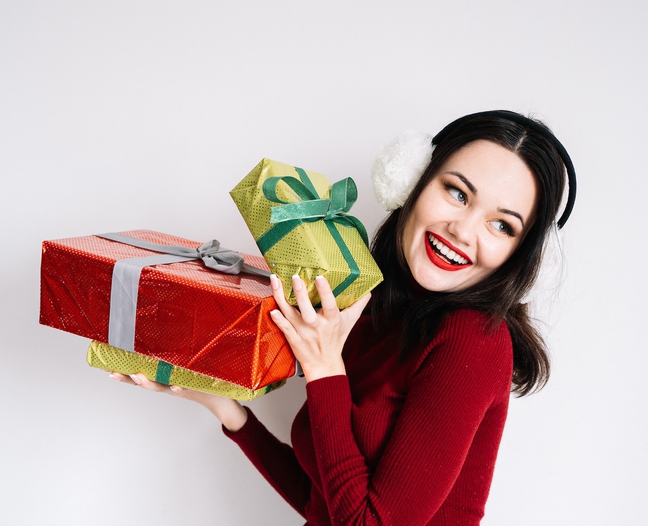 Young woman is holding a presents and smiling.