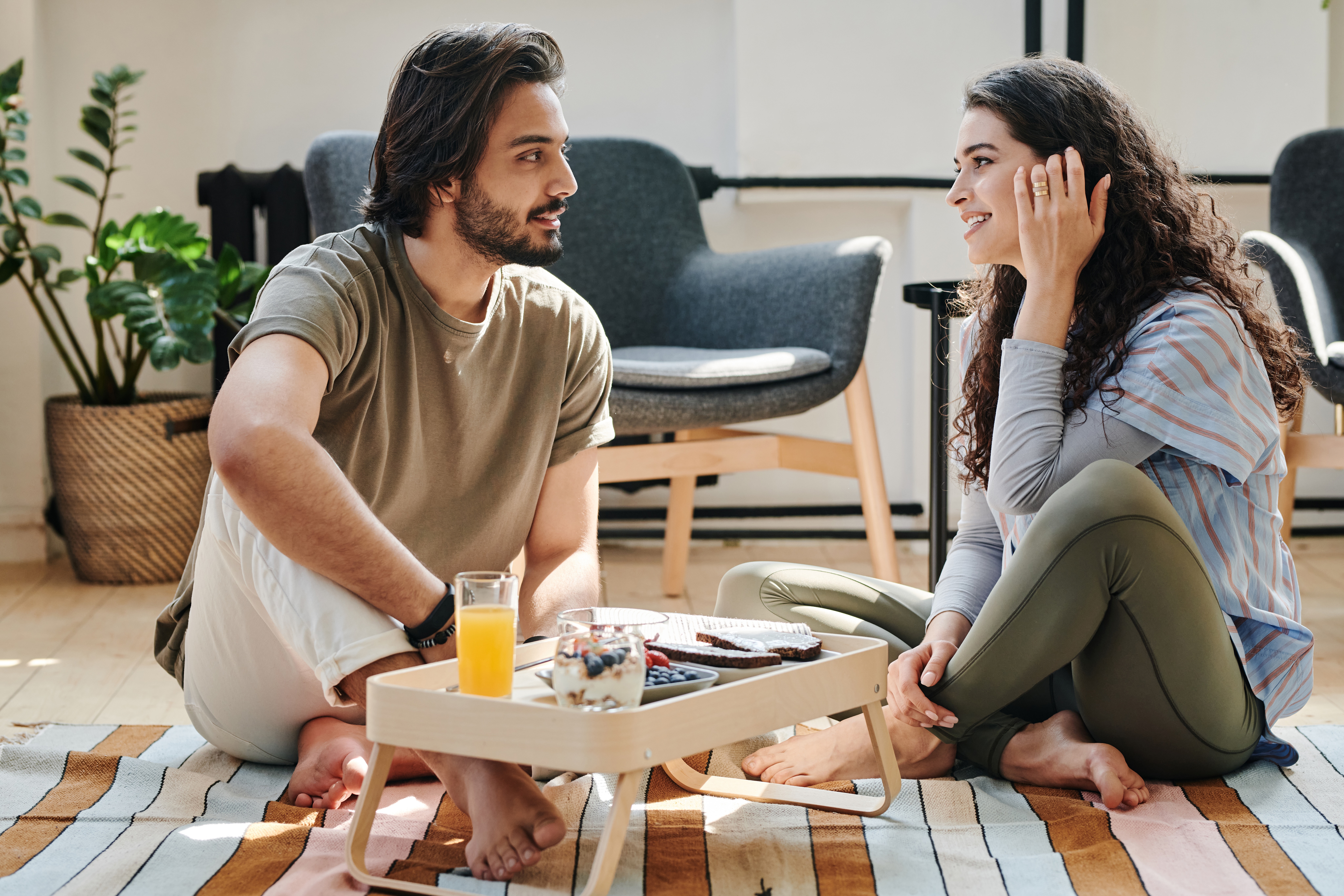 Young couple are seating and talking at living room floor.