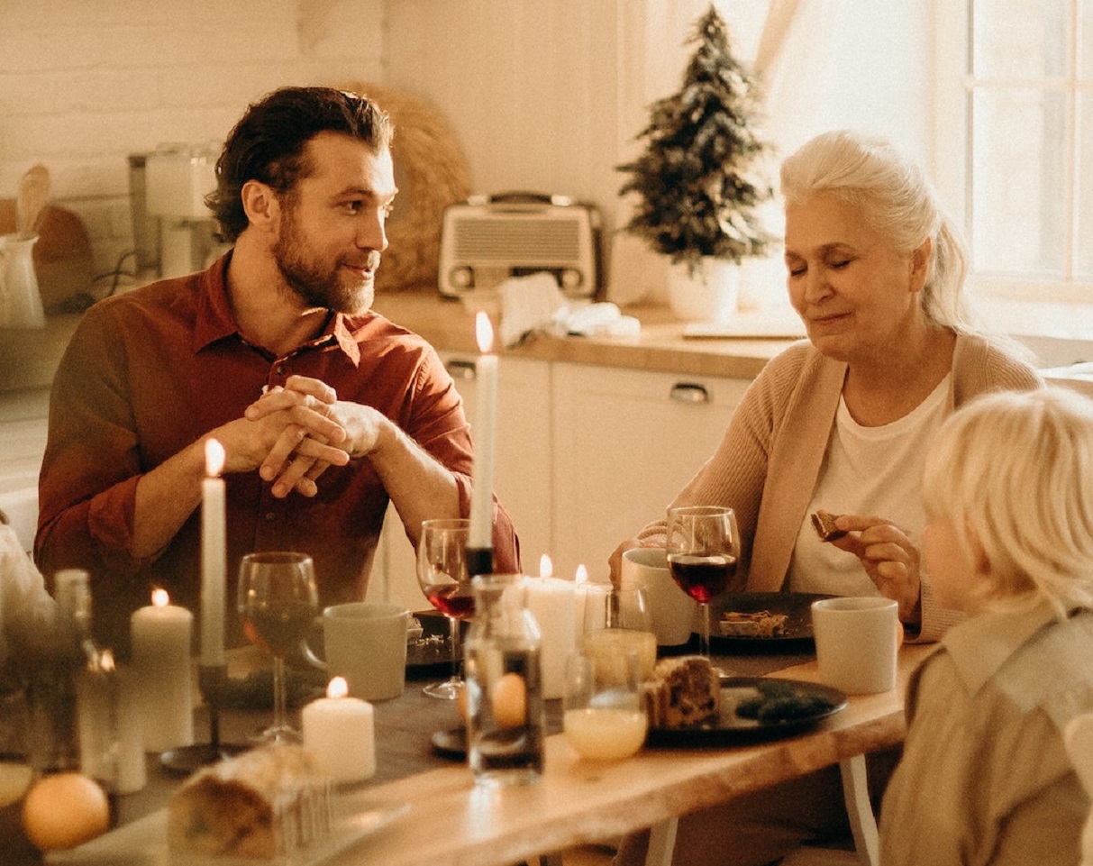 Young man is having a conversation with senior woman ,seating on dinner table.