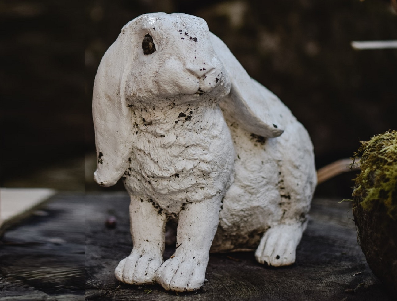 White bunny statue seating outside in the yard.