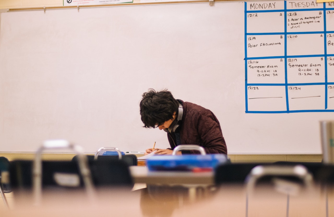 Young student is seating alone in classroom.