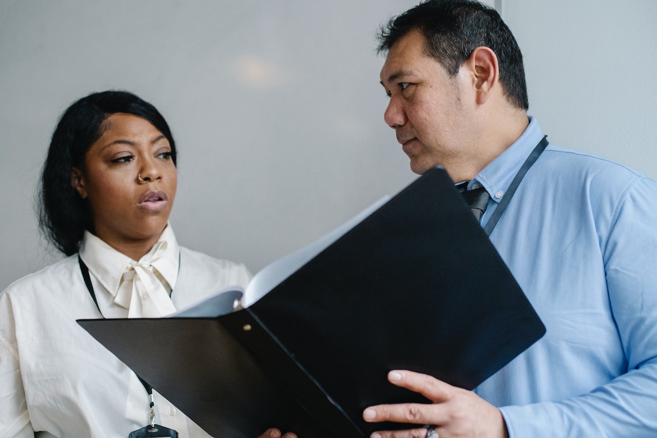 Man holding a document and talking to a woman who is looking at him.