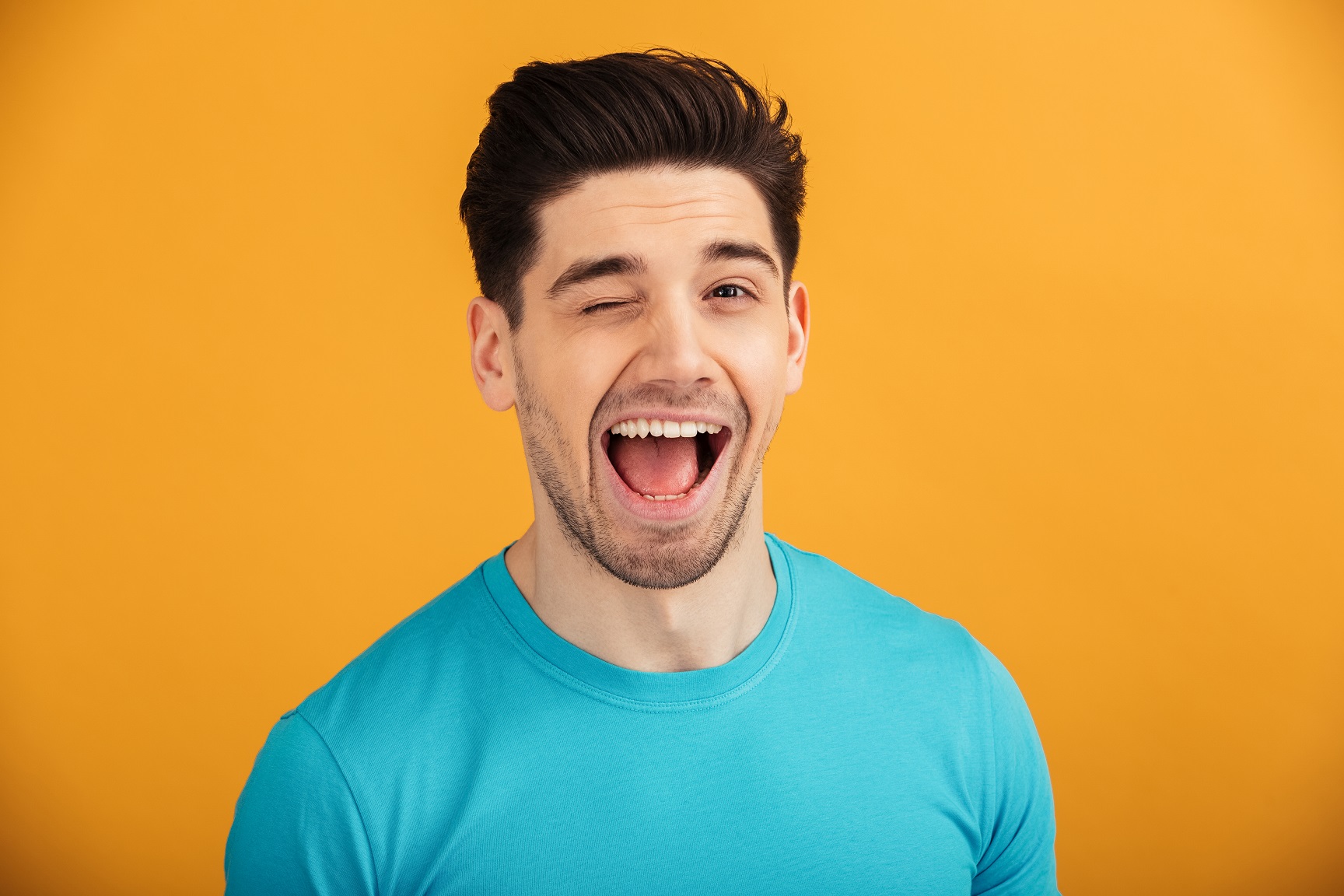Bearded man is winking on orange background.