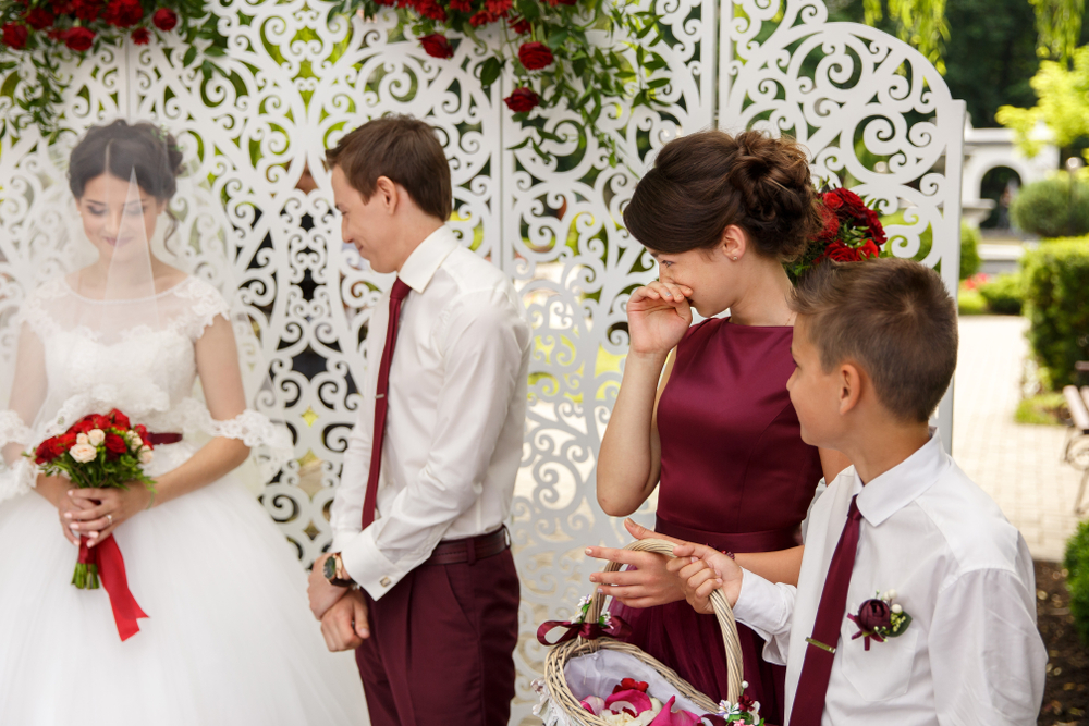 Young girl in bourbon dress crying standing by the bride and groom