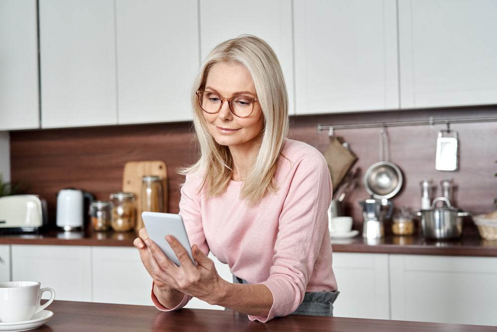 Mature older lady in pink sweater holding mobile phone