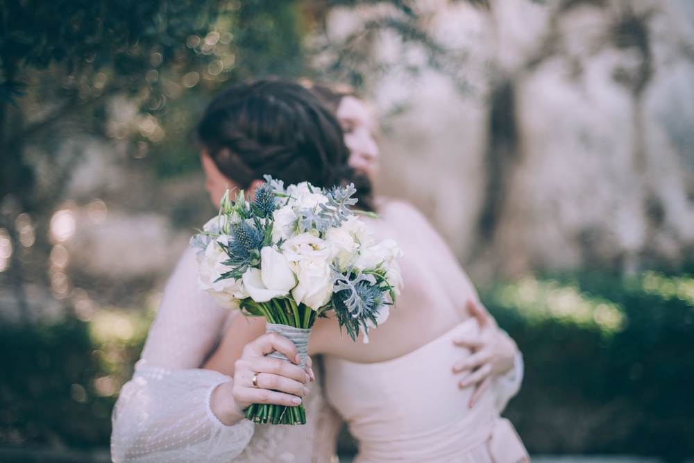 Bride hugging guest in similar dress and hair to her own at a wedding