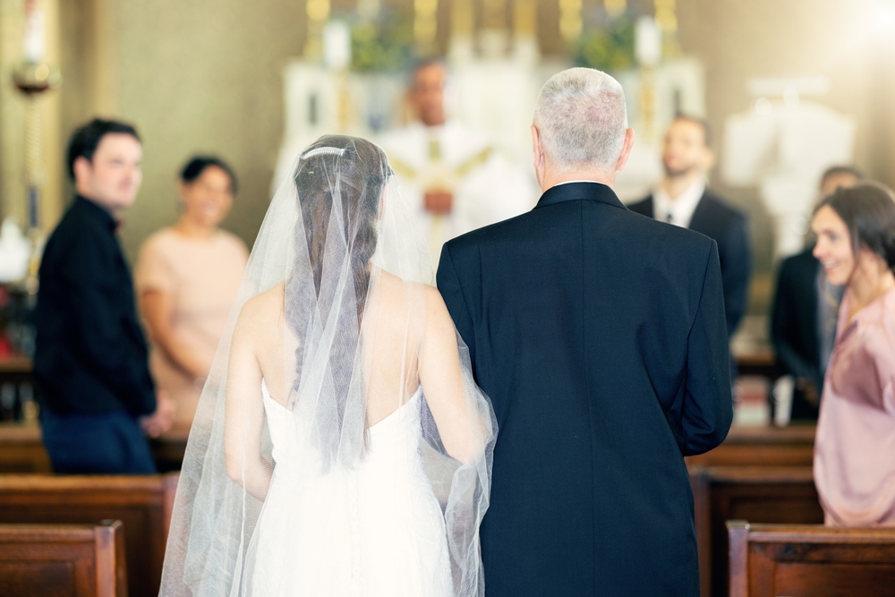 father and the bride walk down an aisle