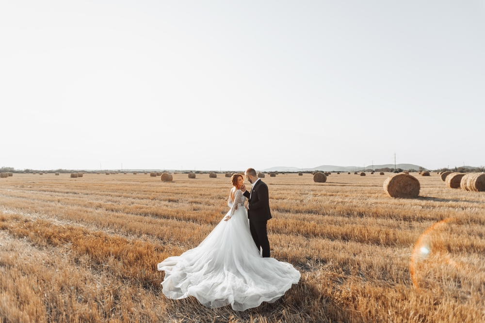 The bride and groom are standing in the field