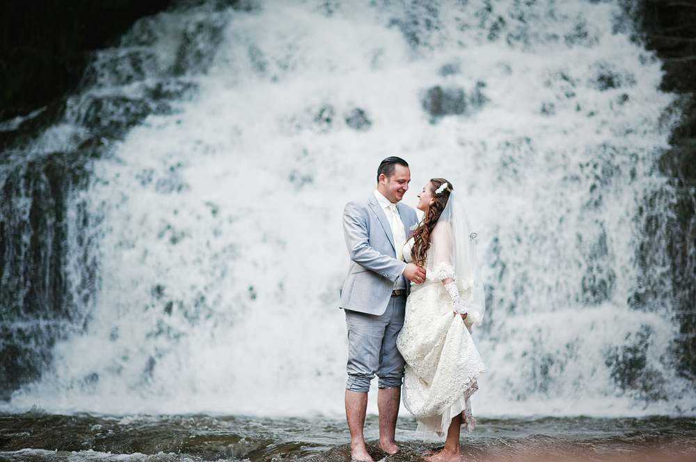 Happy newlyweds near waterfall