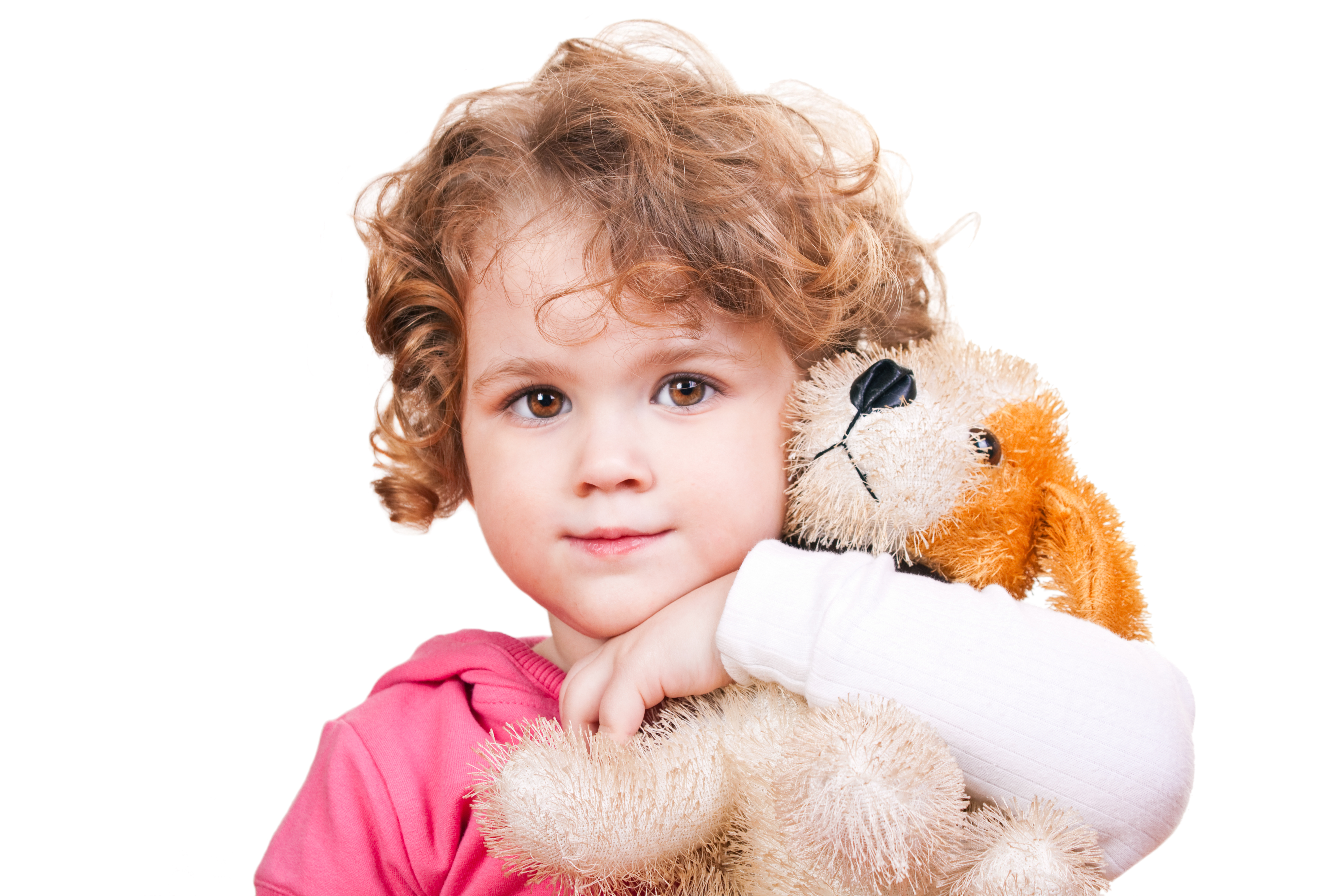 Small girl with brown hair and pink pajamas is holding a dog toy at her hands.