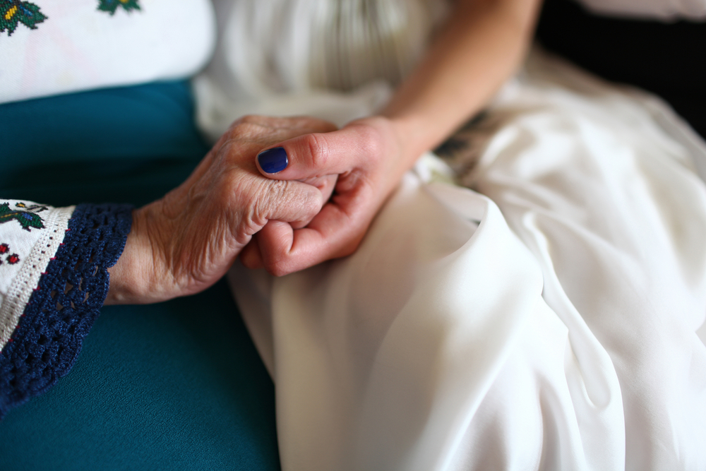 bride and her grandmother sitting holding hands