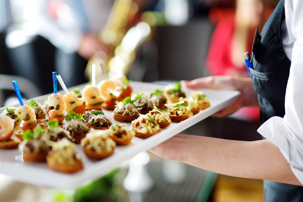 Waiter carrying plates with meat at wedding