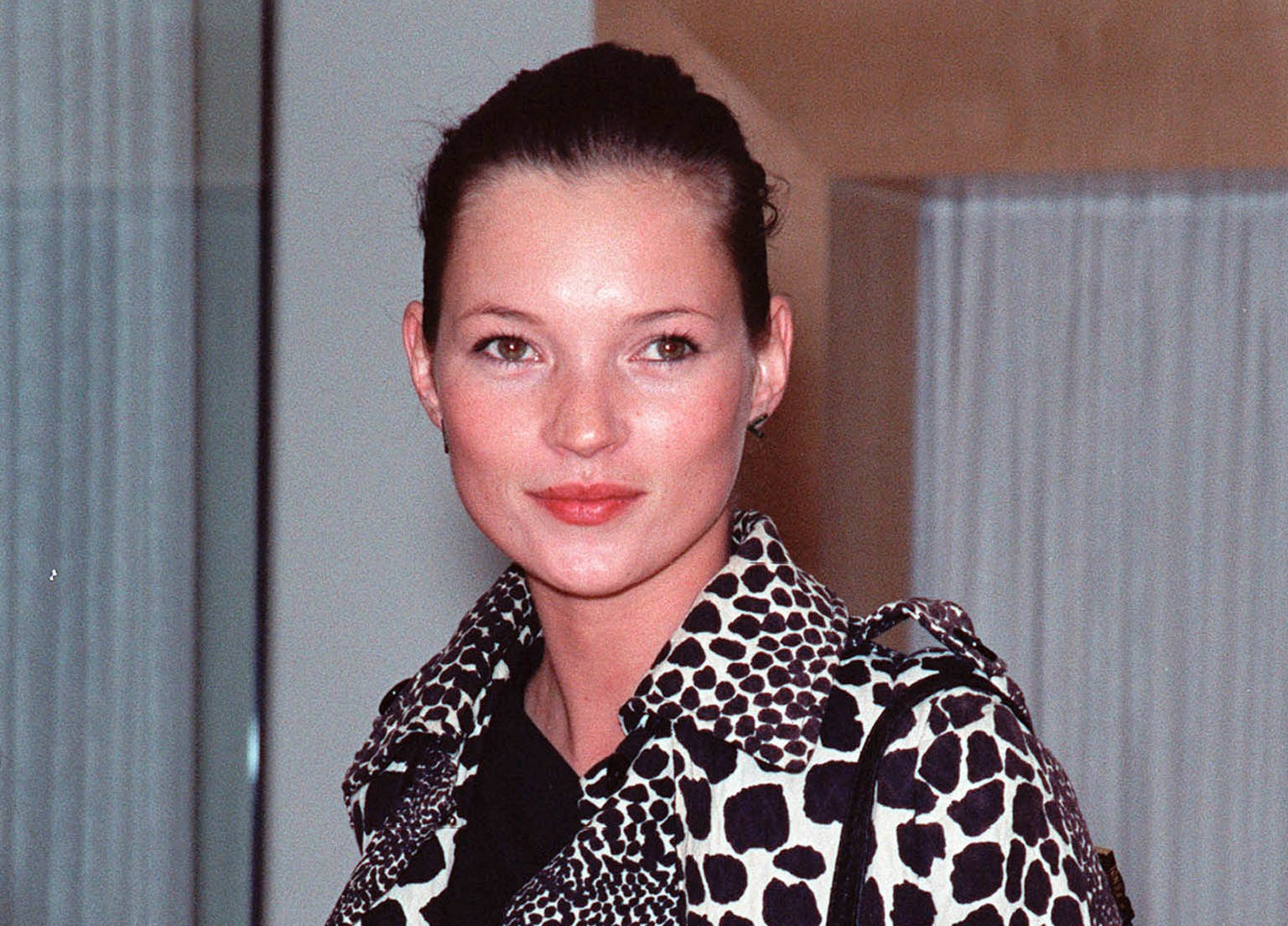 Kate Moss wearing white coat with black dots ,looking at side and smiling - 1999
