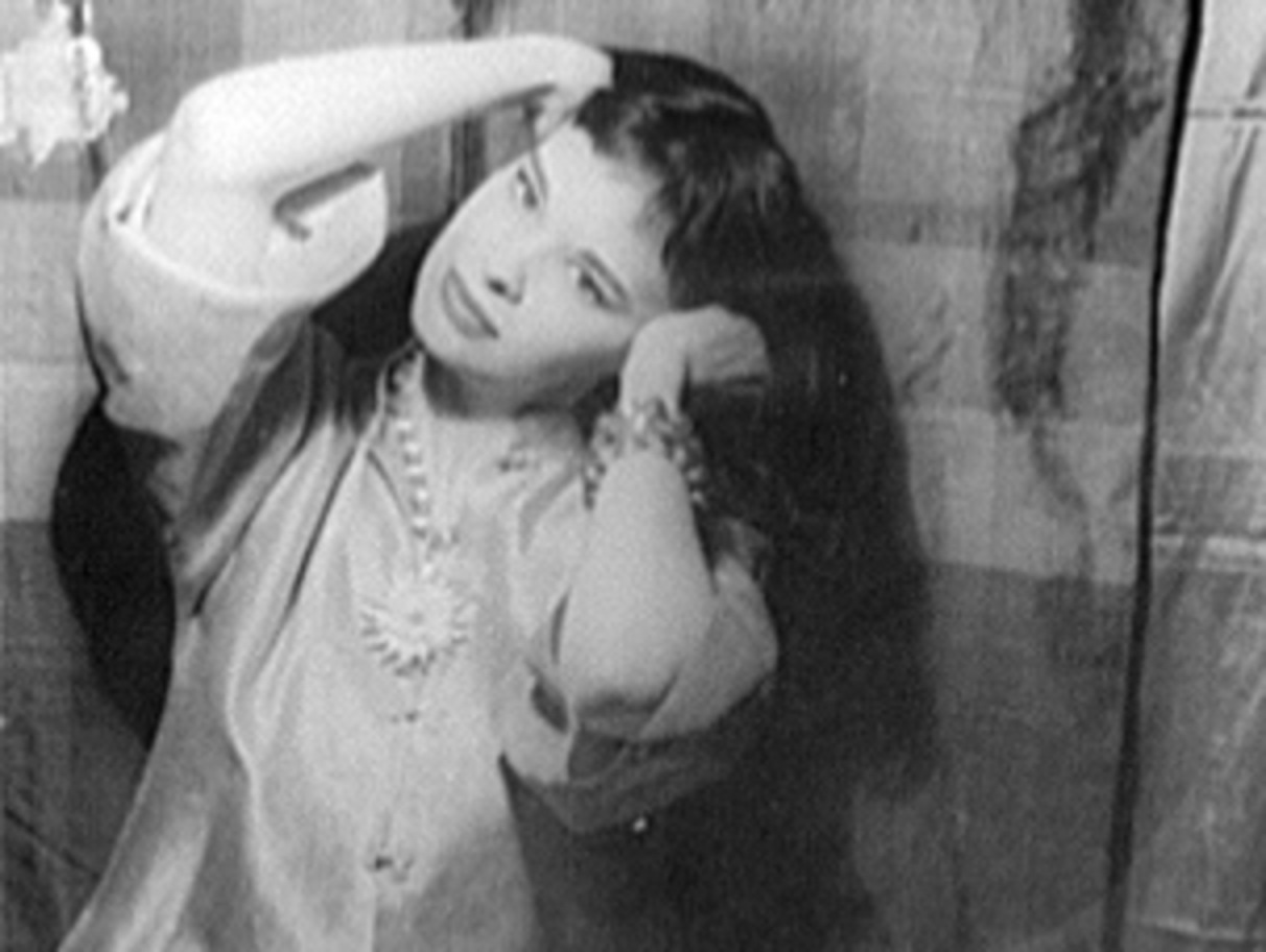 B&W photo of Gloria Vanderbilt holding her hair ,looking at camera.