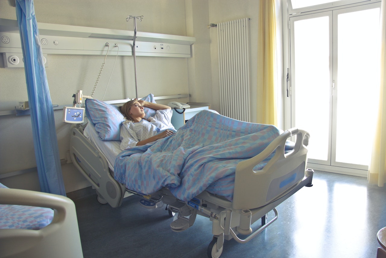 Young woman is laying in hospital bed and looking at side.