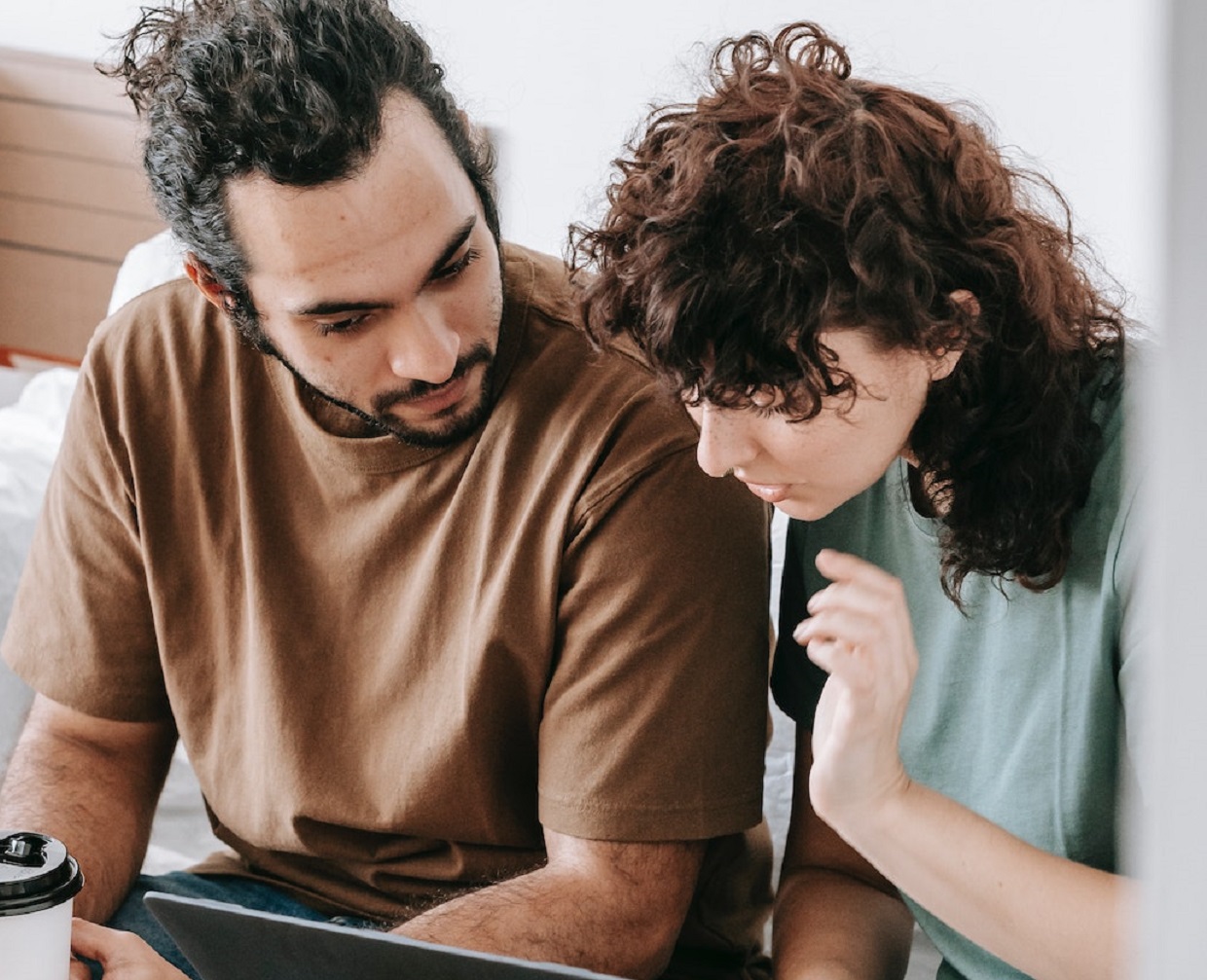 Man is seating next to a woman and looking at laptop.
