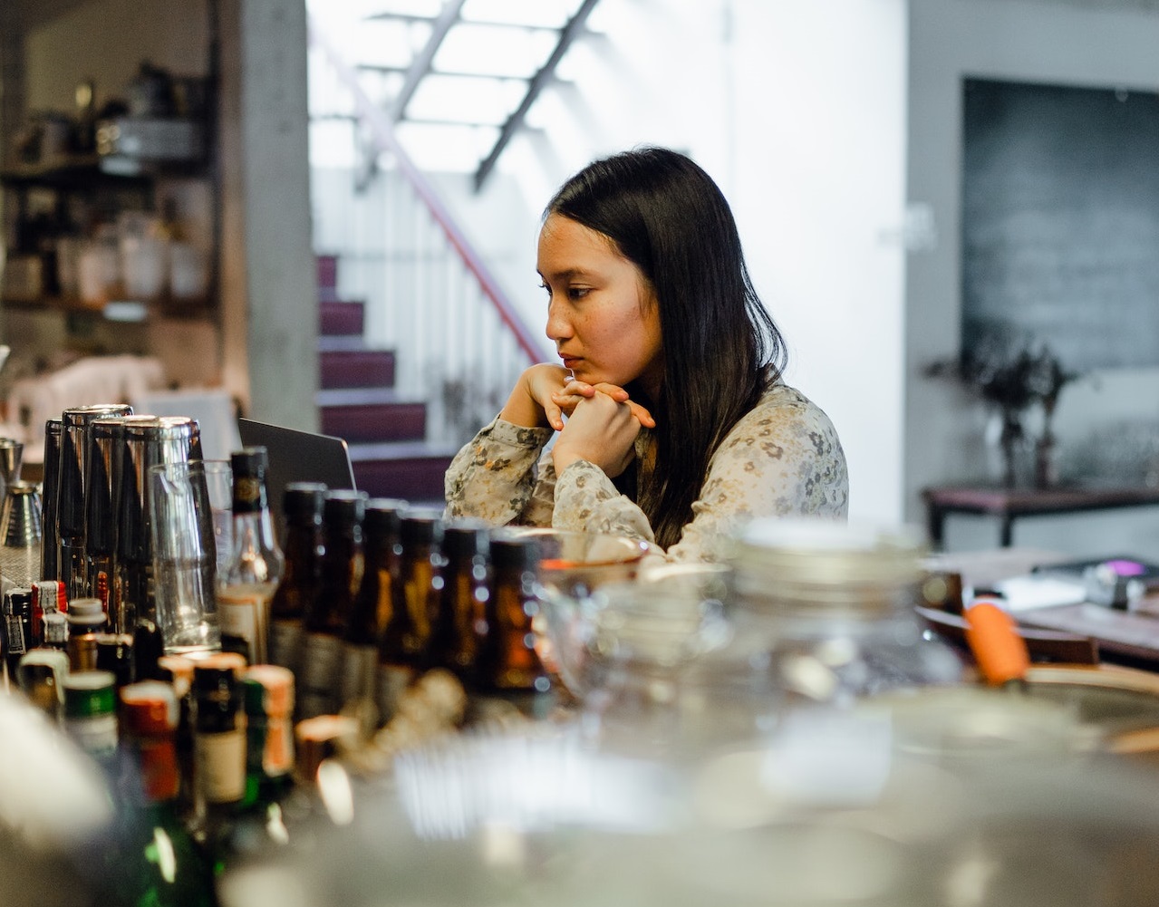 Sad woman is seating alone at bar and looking down.