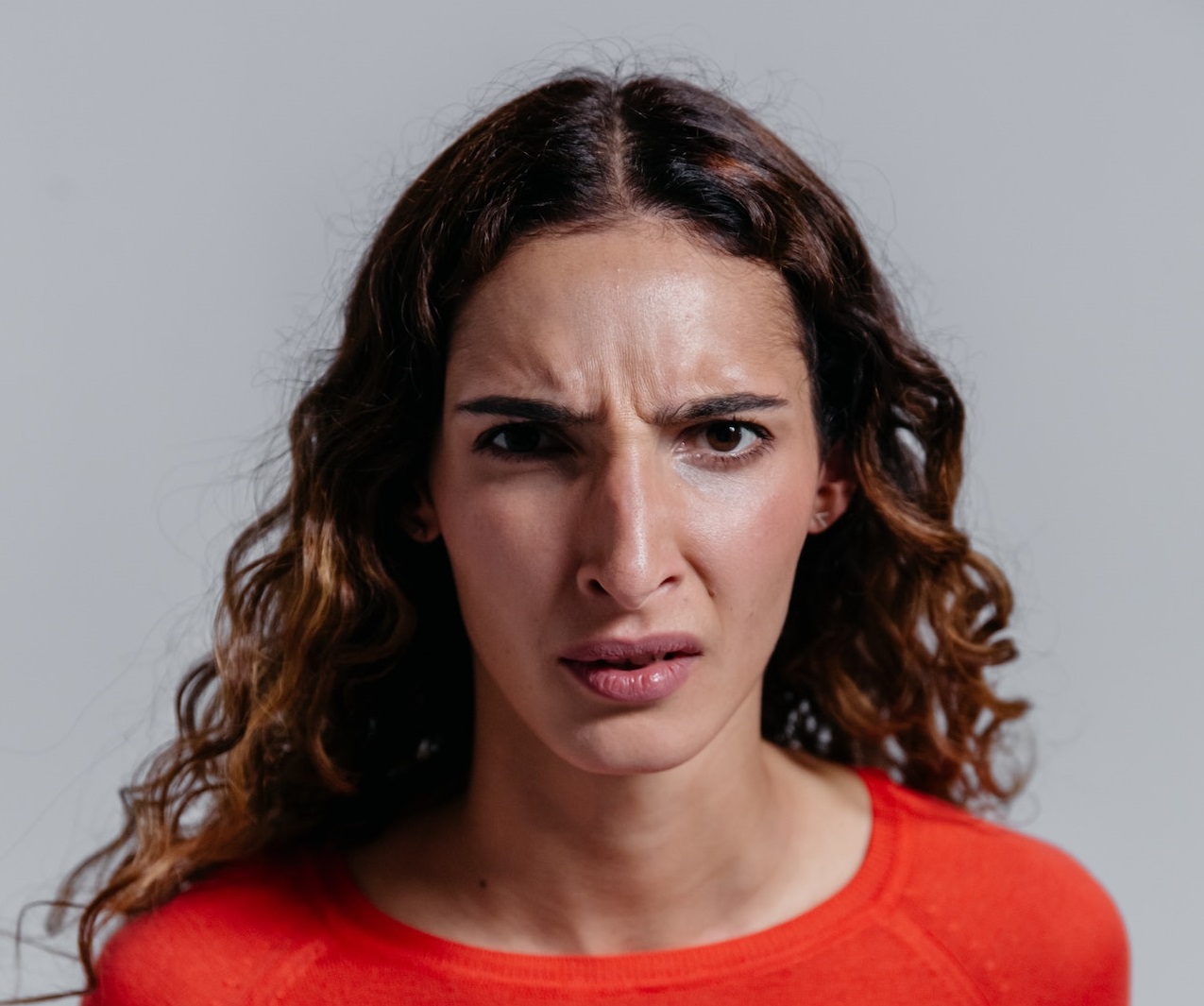 Angry woman with red sweater is looking at camera.