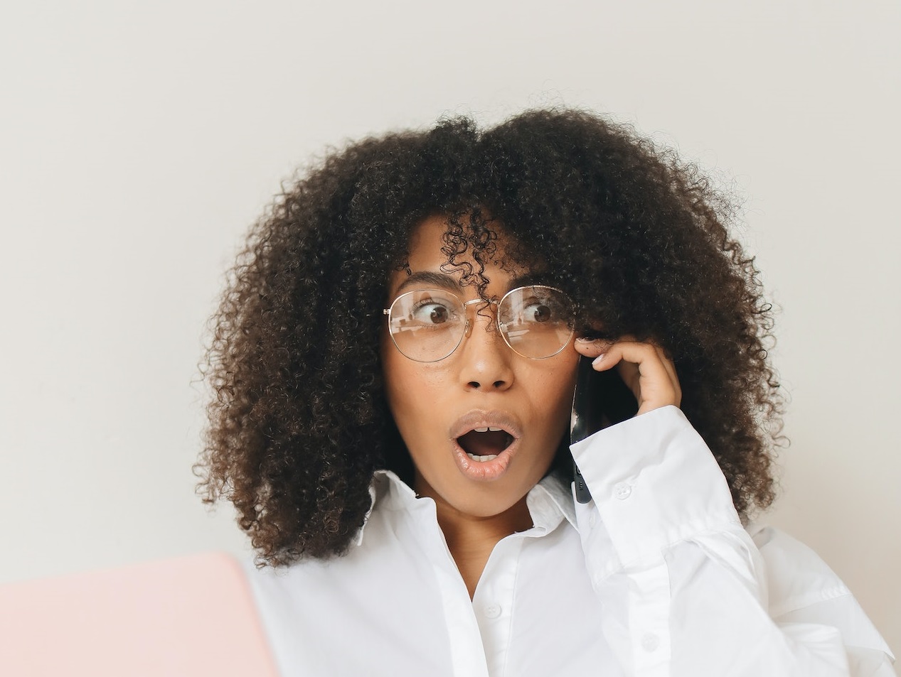 Shocked black woman is talking on the phone and looking at side.
