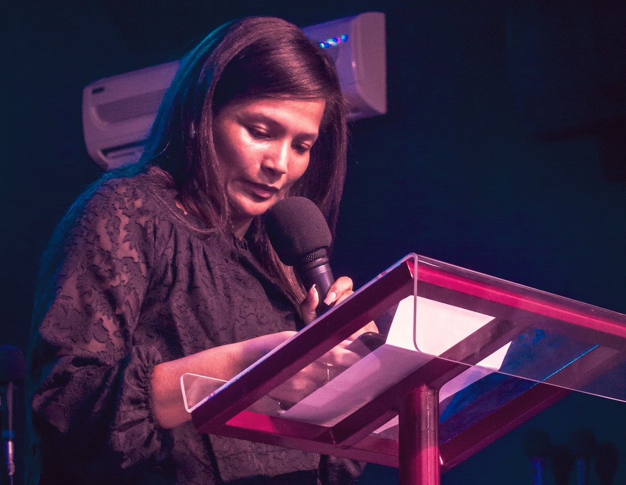 Woman is reading and talking on the microphone.