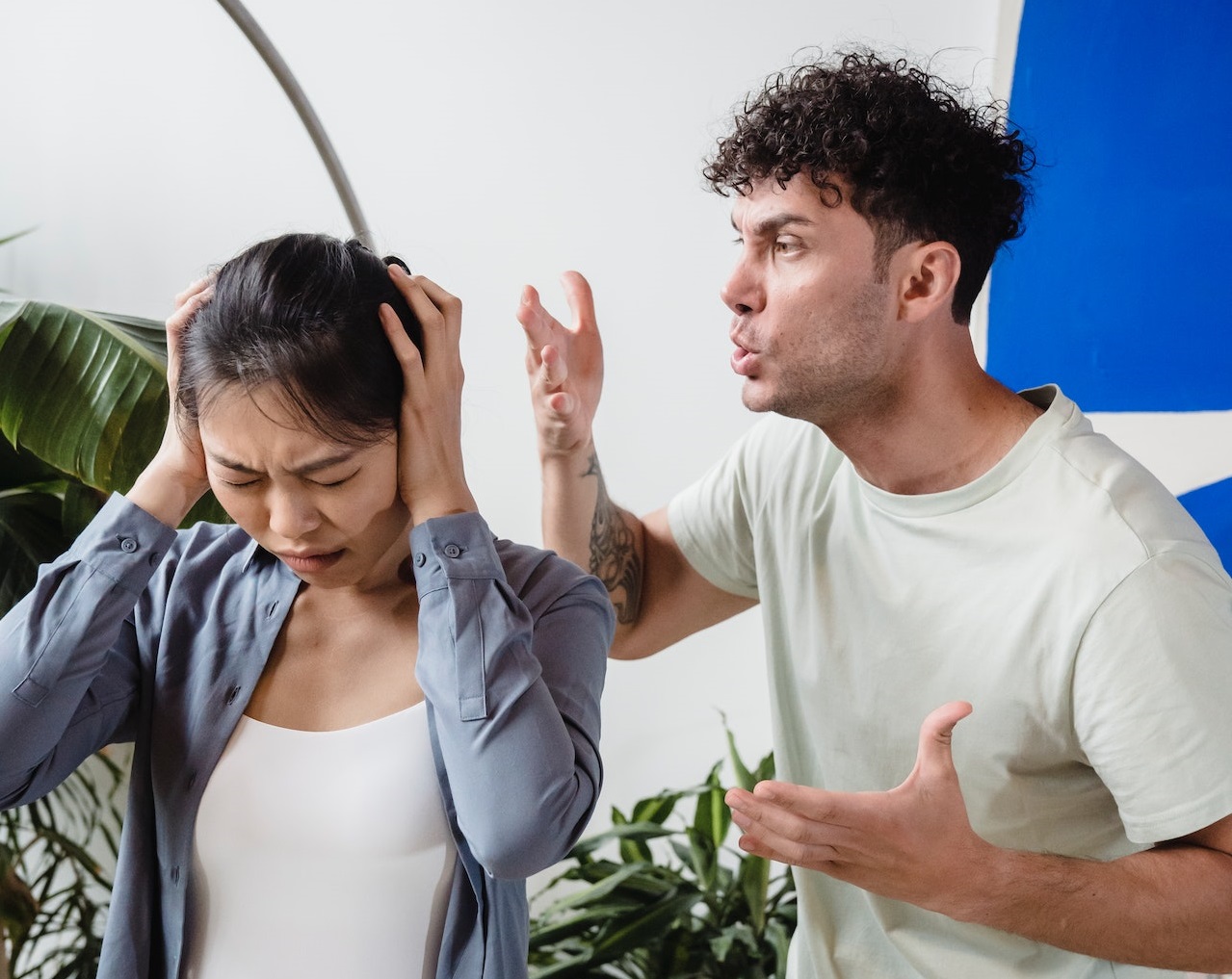 Young man is screaming at woman who is covering her ears.