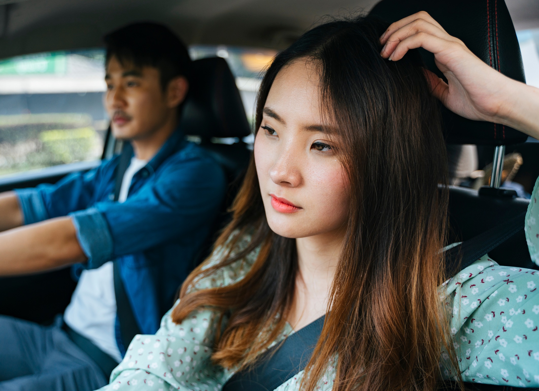 Sad couple are seating inside a car and looking at front.