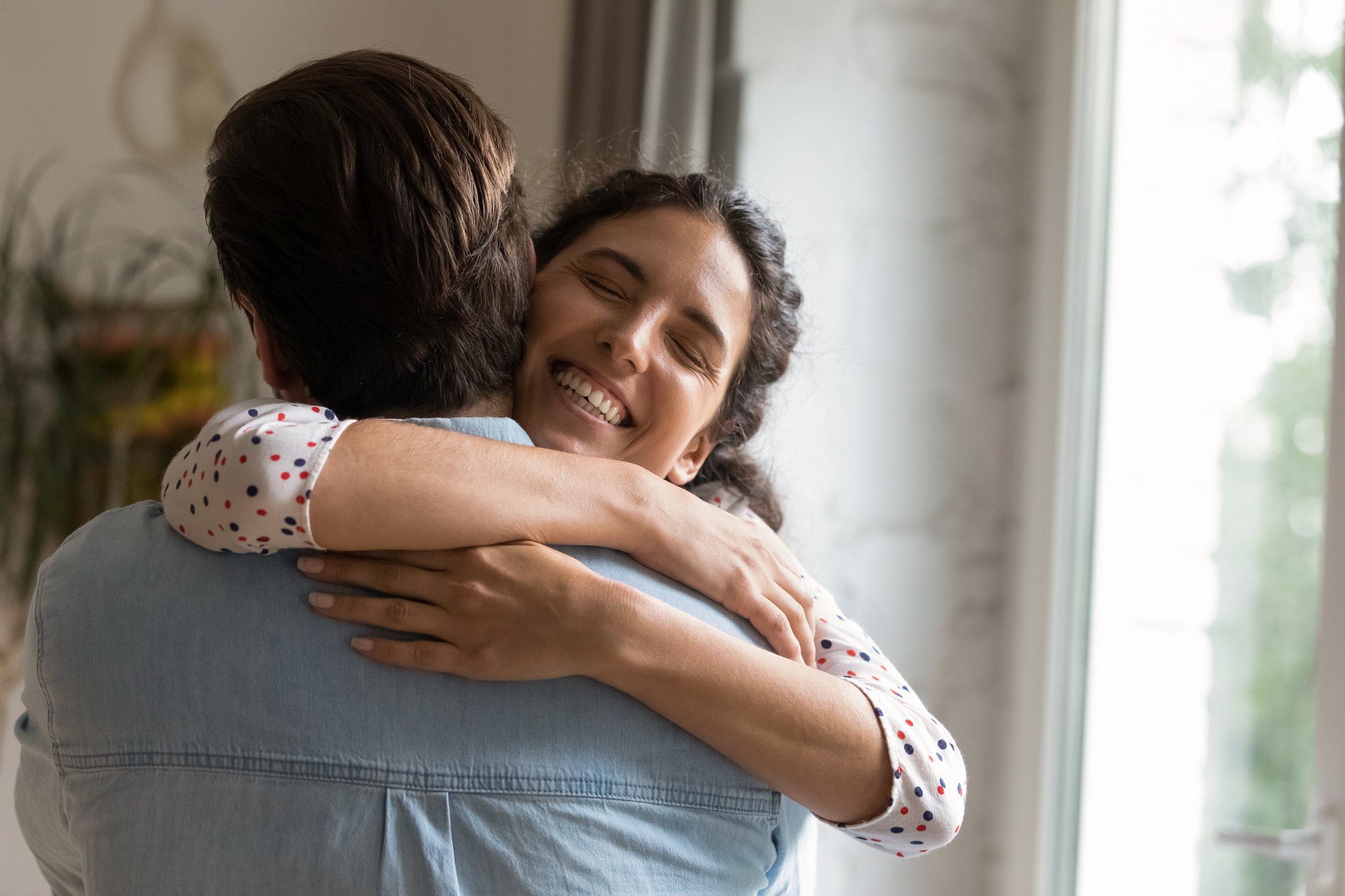 Woman  strong hugging a man in blue shirt.