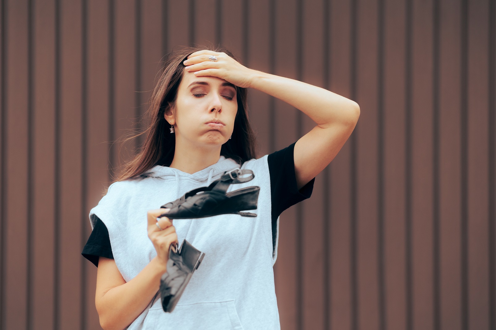 Woman is feeling upset holding black shoes in her hand.