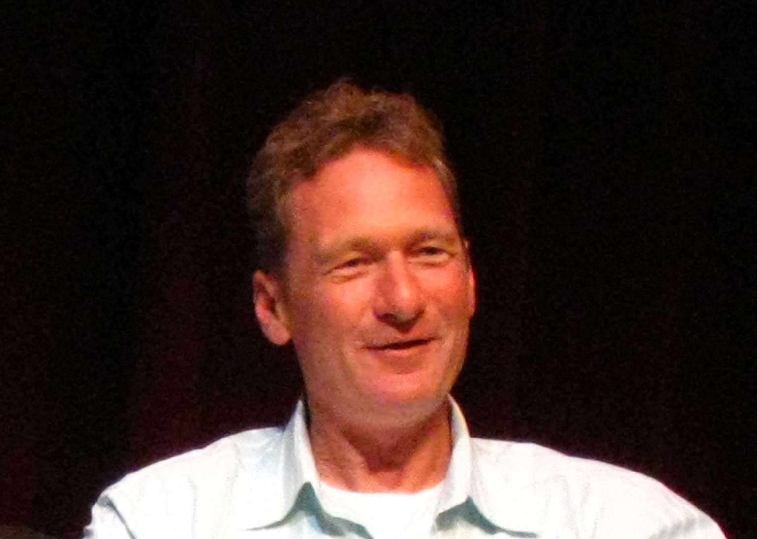 Ryan Stiles is looking at side and smiling on black background - 2008.