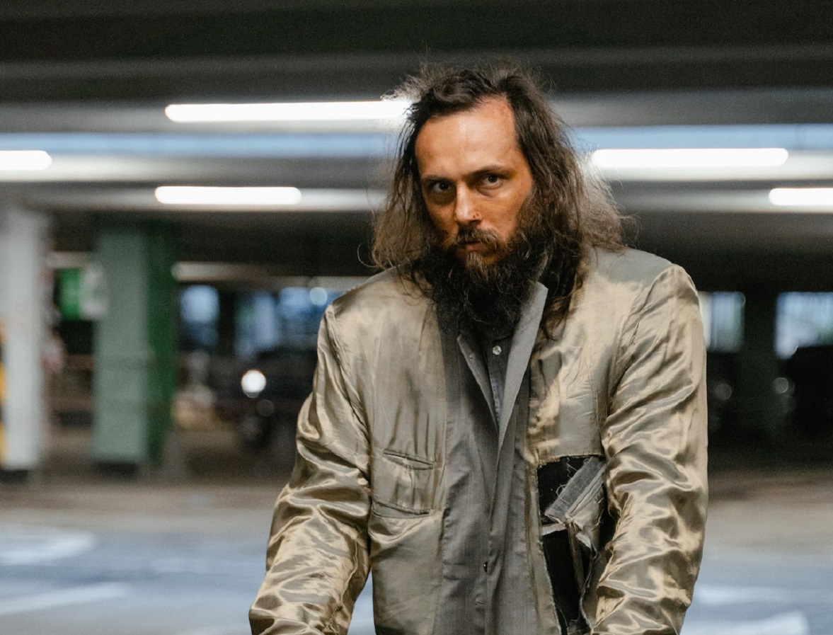 A homeless man is standing in parking lot.