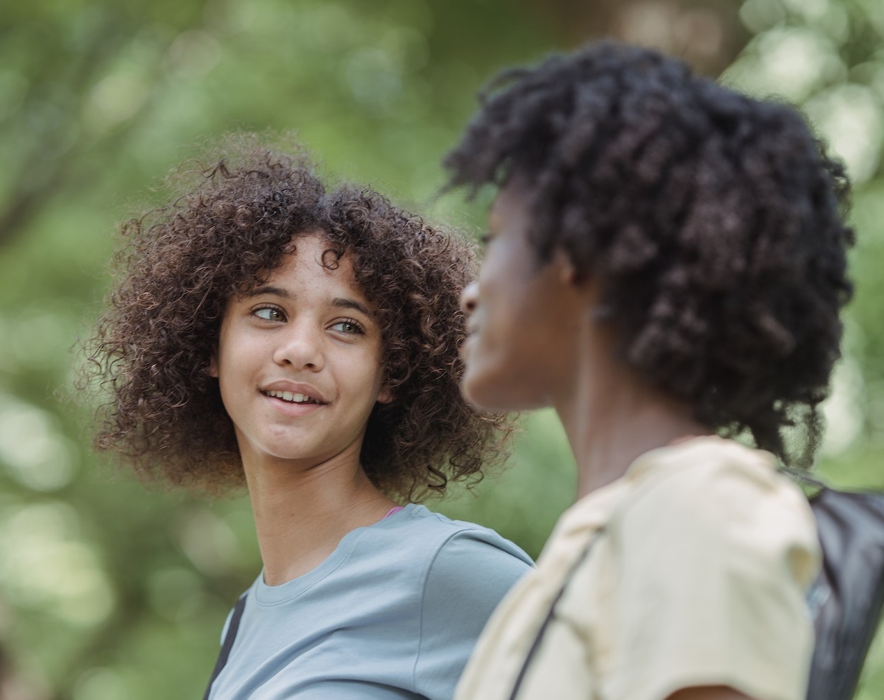 Two girls are talking and walking outside.