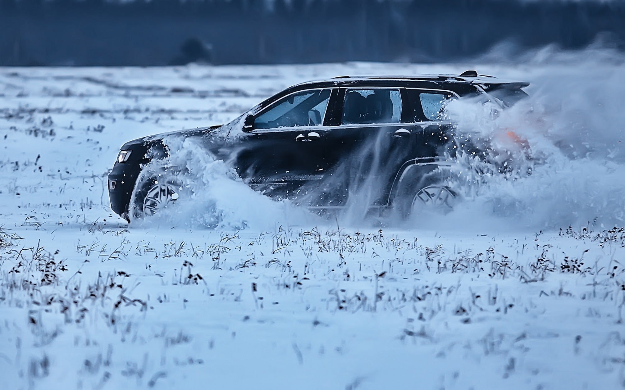 Black SUV is driving fast on snow.