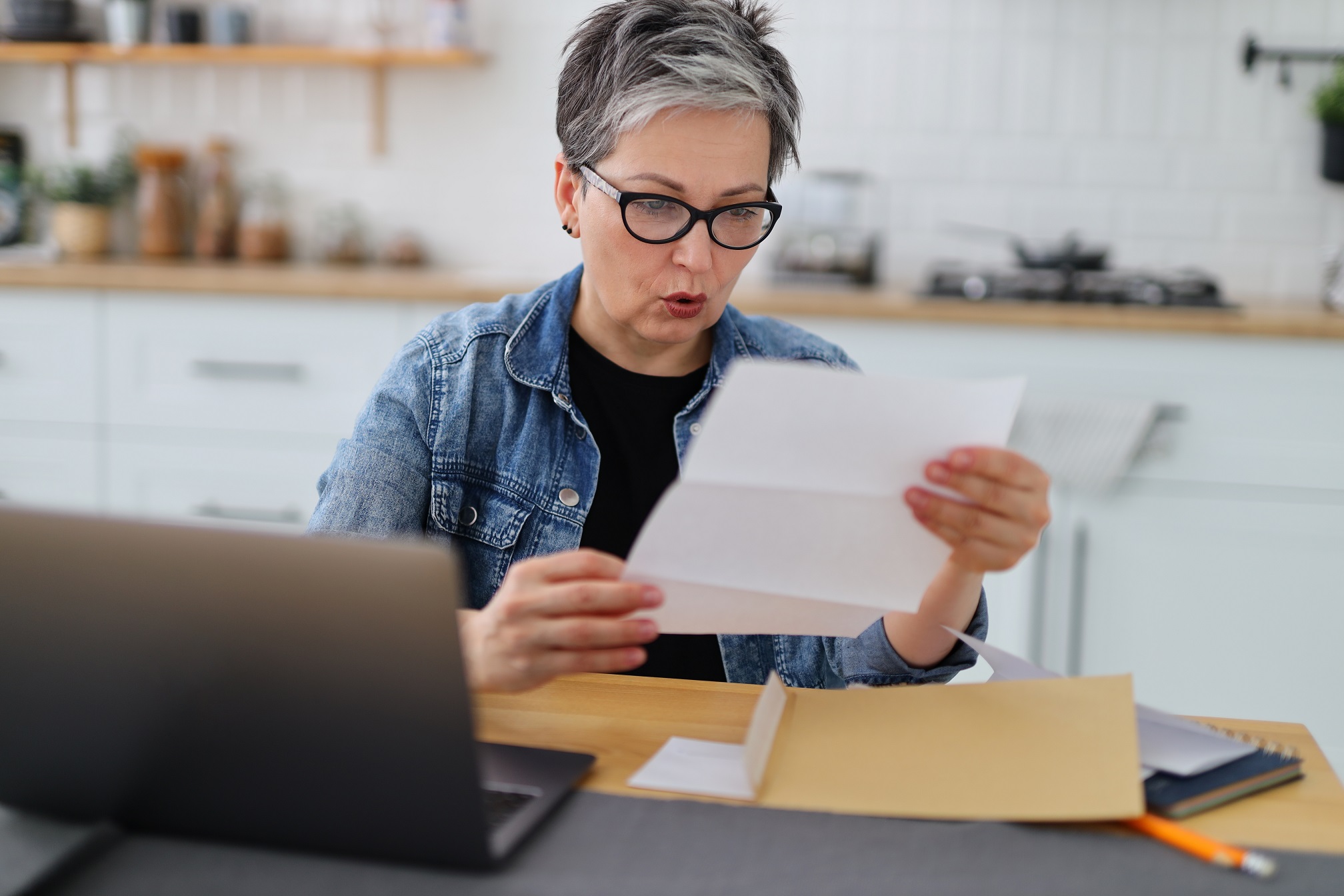 Woman is looking surprised ,holding a document in her hands.