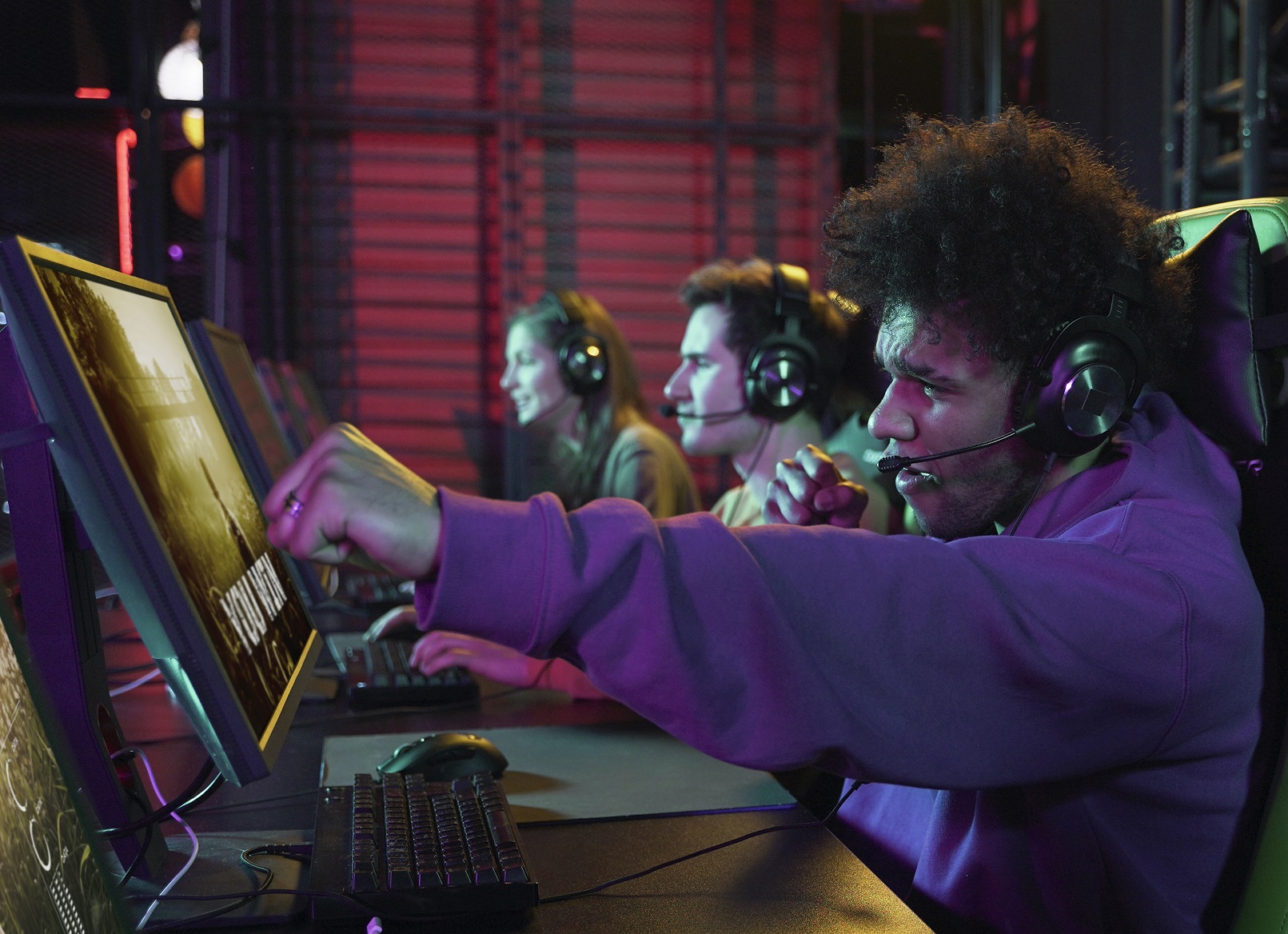 Young people with headphones are seating and playing games n PC.