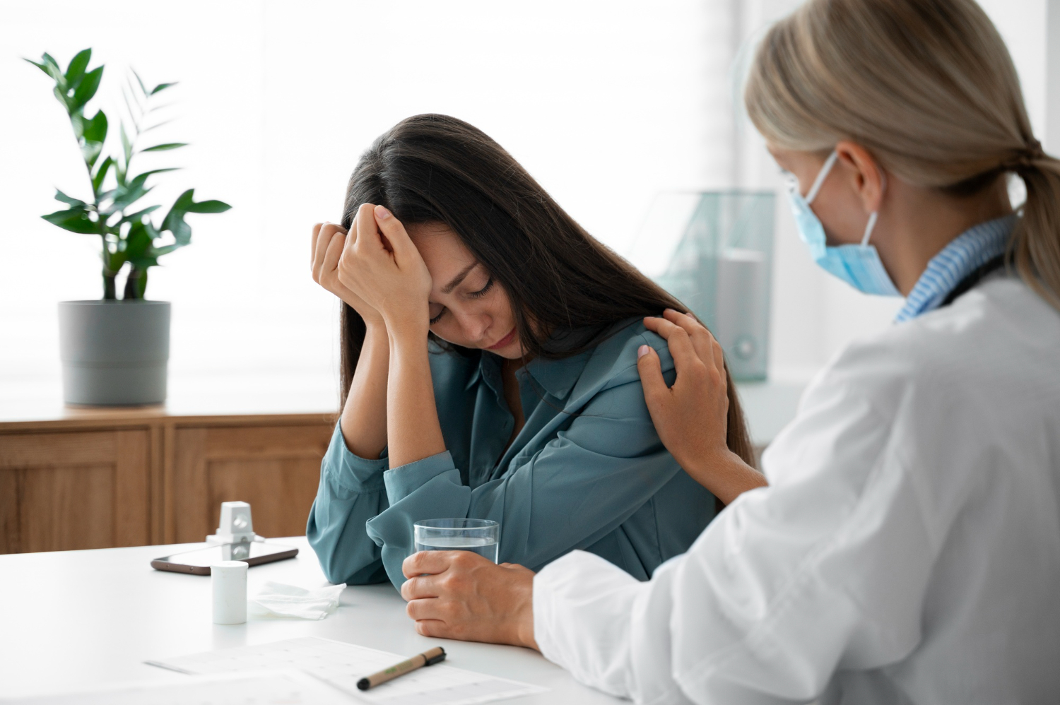 Female doctor is talking with a female patient , looking upset at her office.