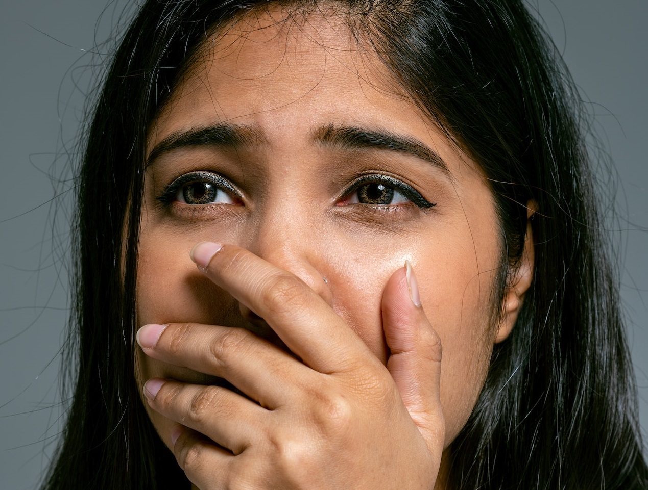 Young woman is covering her mouth with her hand.