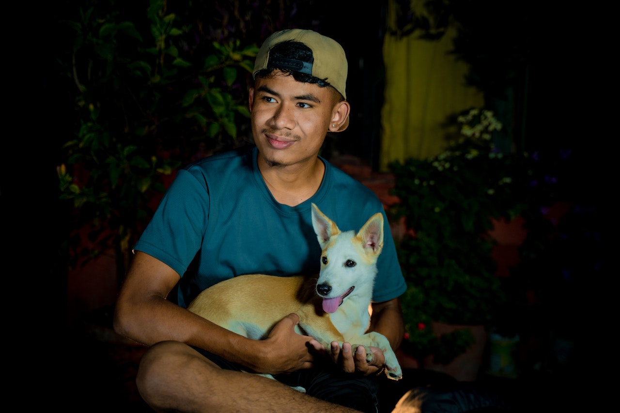 Young man is holding a small dog in his hands.