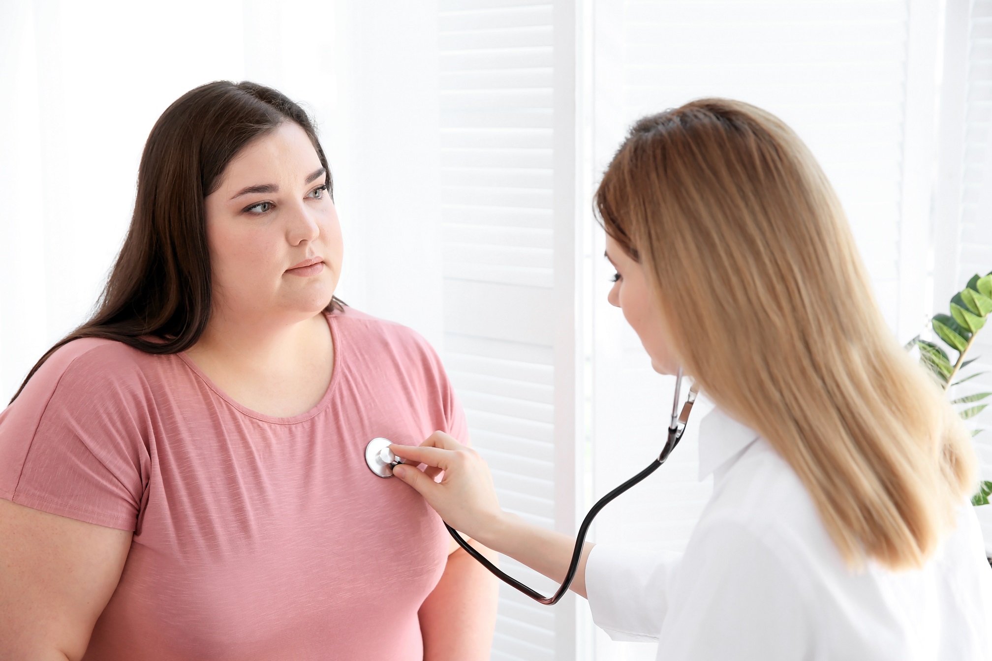 Female doctor is listening to big (fat) female patient's heartbeat at her office.