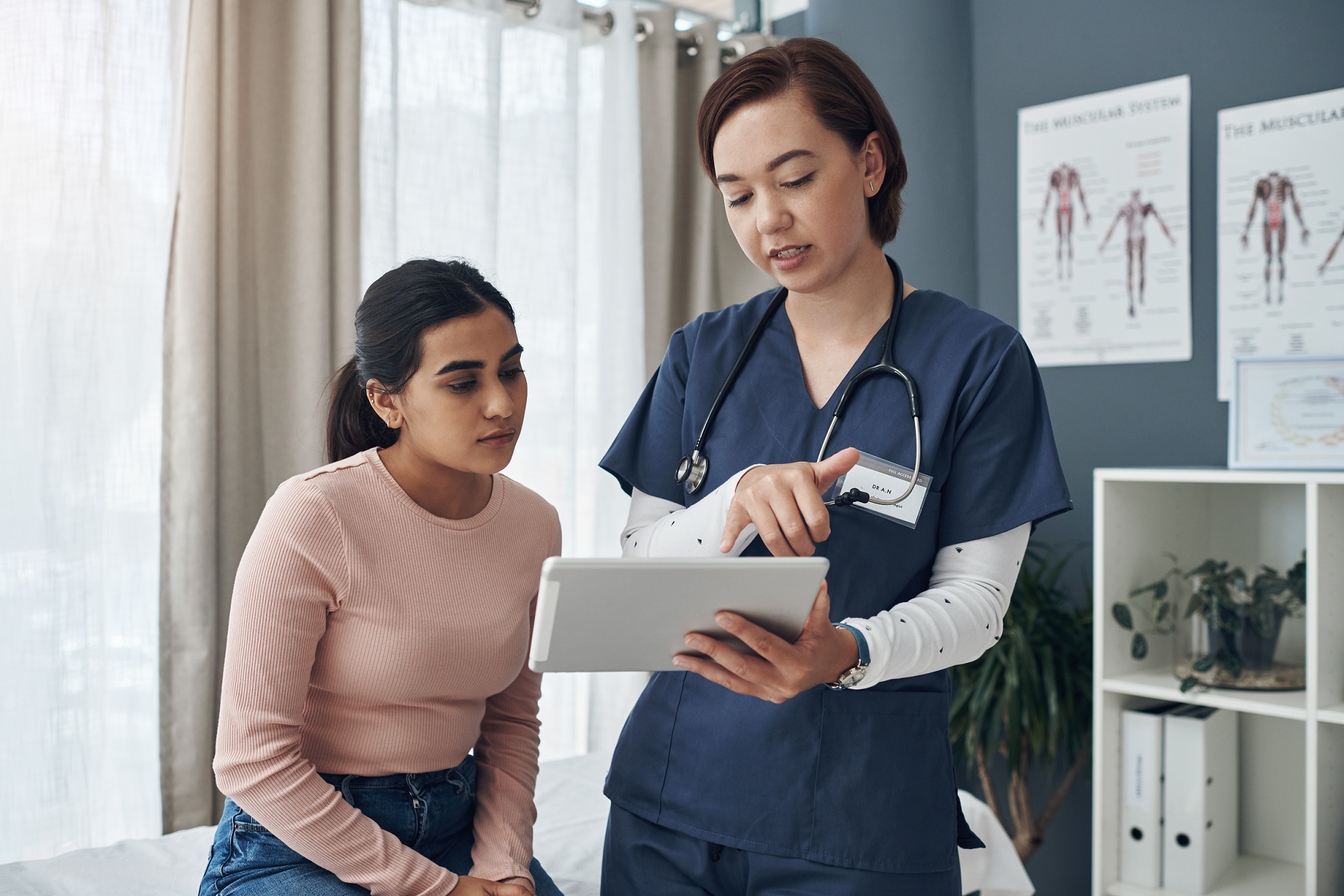 Female patient is talking with female doctor in blue uniform holding results.